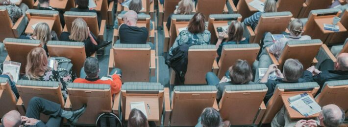 Image shows a lecture hall crowded with students