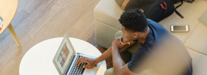 young male student using his laptop in a campus learning space.