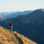 Hiker in high altitude rocky mountain landscape. Summer adventures on the Italian French Alps, toned image.